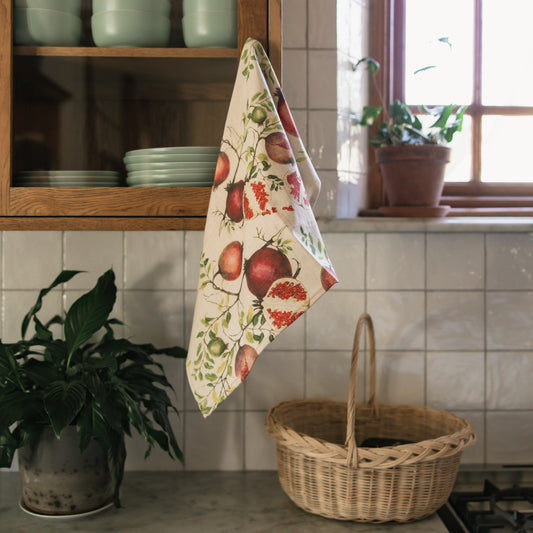 Kitchen scene with a towel hanging on a cabinet, a basket on the counter, and a window in the background.