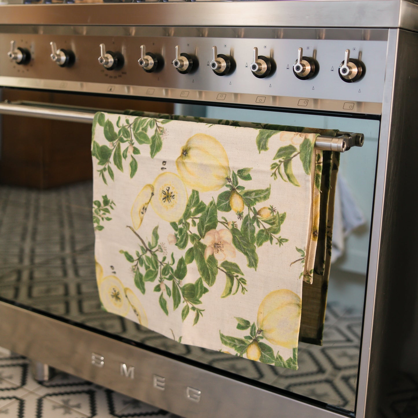 Stainless steel Smeg oven with a floral towel hanging on the handle, kitchen setting.