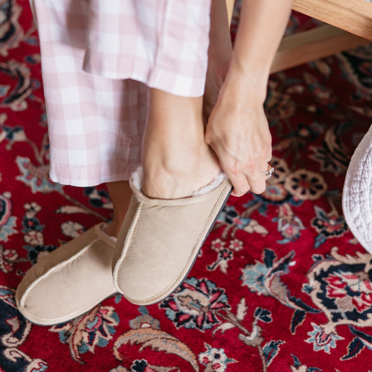 Person wearing beige shoes on a red patterned rug